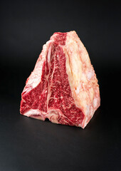 Raw dry aged wagyu porterhouse beef block offered as close-up on black background with copy space