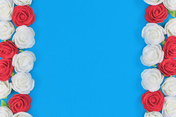 Red and white foam rose flowers on sides of blue background with blank copy space