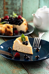 Berry cheesecake cut on deep blue plate with teaware background
