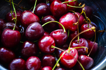 Red ripe cherries with twigs in a Cup and on the table