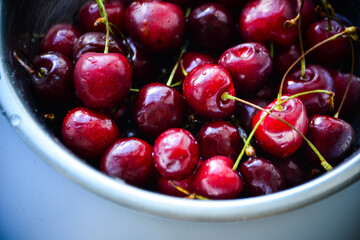 Red ripe cherries with twigs in a Cup and on the table