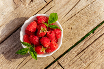 Freshly Picked Raspberries in a bowl on rustic wooden background.