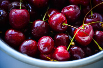 Red ripe cherries with twigs in a Cup and on the table
