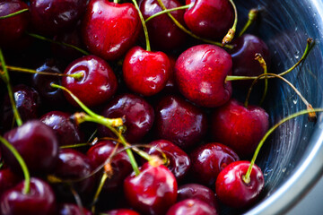 Red ripe cherries with twigs in a Cup and on the table