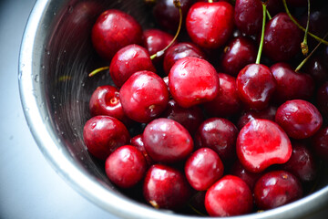 Red ripe cherries with twigs in a Cup and on the table