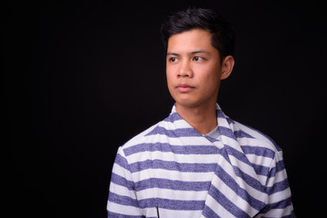 Portrait of young Asian man against black background