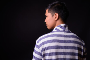 Portrait of young Asian man against black background