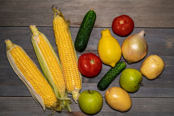 Assortment of fresh fruits and vegetables such as apple, cucumber, tomato, corn, potatoes, onions. Mixed vegetables and fruits