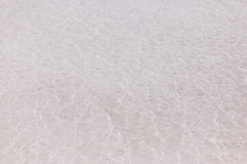 Crystal clear sea water and white sand. Small waves.