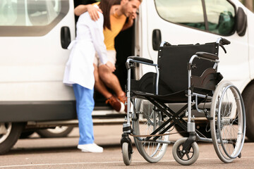 Fototapeta na wymiar Doctor helping handicapped man to sit in car