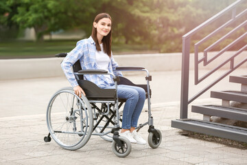 Young woman in wheelchair near stairs outdoors