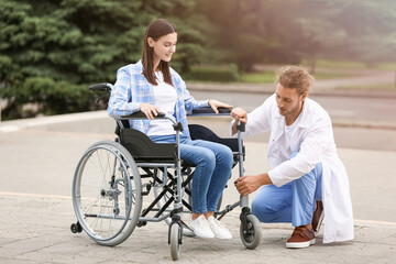 Doctor and young woman in wheelchair outdoors