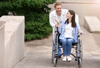 Doctor and young woman in wheelchair outdoors
