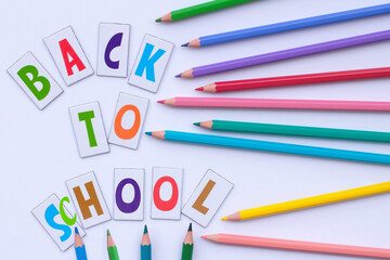 Back to school. Letters and colorful pencils on a white background. Flat lay. Education concept