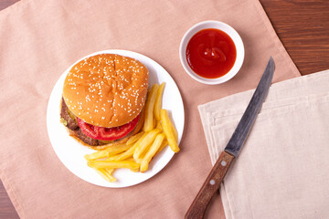 traditional fat burger and french fries on beige textile cloth