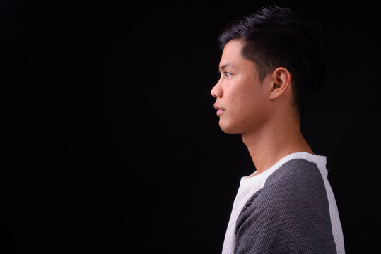 Portrait of young Asian man against black background