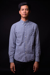 Portrait of young Asian businessman against black background