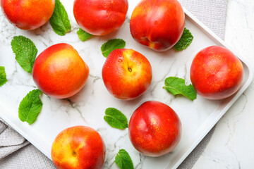 Tray with sweet ripe nectarines on table