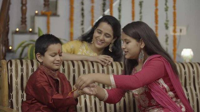  sister tying rakhi, Raksha bandhan to brother's wrist during festival or ceremony - Raksha Bandhan celebrated across India as selfless love or relationship between brother and sister