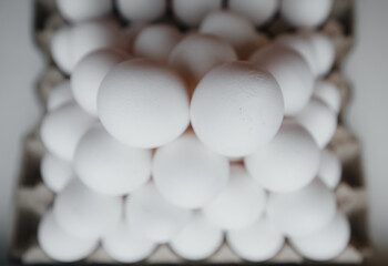 A tray of white fresh eggs in close-up laid out by a pyramid on a cardboard package. Agricultural industry