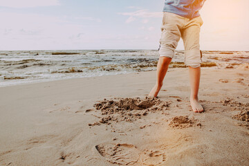 Little boy is playing on the beach by the sea. Vacation and lifestyle concept. A child on vacation spends time at the seaside, playing in the sand.