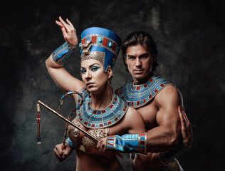 Woman and man in blue and gold egyptian costumes, posing in the studio with black walls