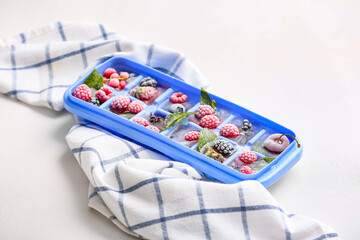 Tray with berries in ice on white background