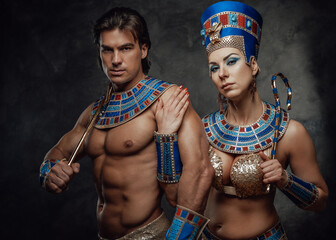 Woman in traditional egyptian costume holds male sholder and the sign of power and royalty.