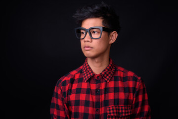 Portrait of young Asian hipster man against black background