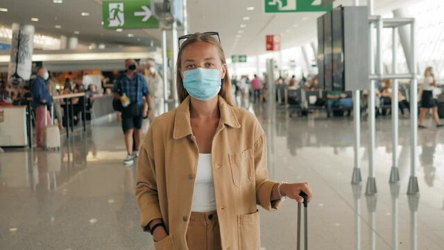 Portrait Of Woman Tourist Travel By Plane, Airport Terminal Timetable, Wearing Protective Medical Mask. Girl Post Covid, Open Boarders After Lockdown, Coronavirus Pandemic