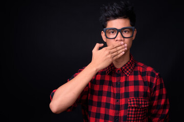 Portrait of young Asian hipster man against black background
