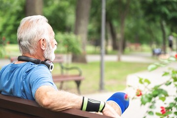 Tired sportsman relaxing on bench after exercising at park