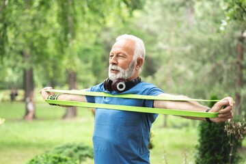 Senior sportsman exercising with resistance band at park