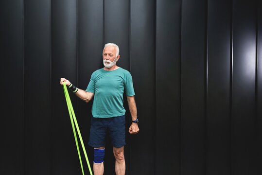 Senior sportsman exercising with resistance band