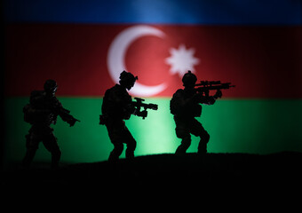 Azeri army concept. Silhouette of armed soldiers against Azerbaijani flag. Creative artwork decoration. Military silhouettes fighting scene dark toned foggy background.