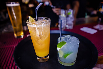Mojito cocktail and orange cocktail with lime and mint in highball glass.