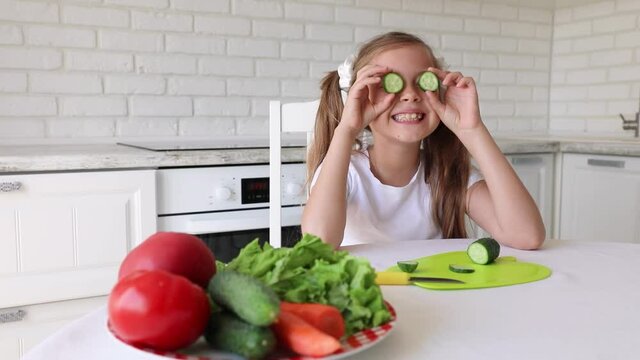 little girl cuts cucumber. Child Preparing Green Salad in Kitchen, Girl Cutting Vegetables Healthy Meal