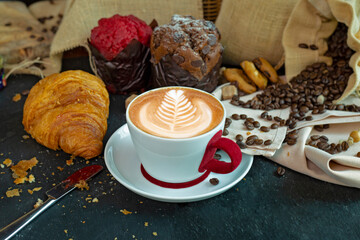 Cappuccino white cup with coffee beans, muffin, croissant, cookies and grapefruit.