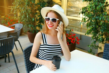 Beautiful young woman calling on smartphone sitting at a table in a cafe with coffee cup