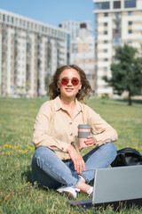 Young woman using laptop on campus lawn