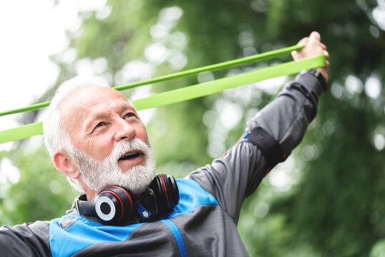 Senior sportsman exercising with resistance band at park