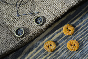 Sewing accessories: buttons, the needle with thread on old wooden table