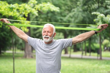 Senior sportsman exercising with resistance band at park