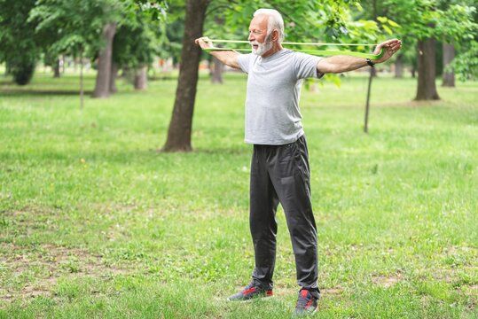 Senior Sportsman Exercising With Resistance Band At Park