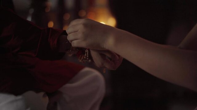 Closeup of hands, sister tying rakhi, Raksha bandhan to brother's wrist during festival or ceremony - Raksha Bandhan celebrated across India as selfless love or relationship between brother and sister