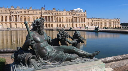 Château de Versailles, avec une statue d'homme, allégorie du fleuve de la Seine, à l’angle d’un des deux bassins du parterre d’eau (France)