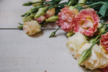 Flower frame made of white and pink eustoms in the style of fine art for an invitation or postcard. Eustoma flowers on a white wooden Board background with space for copying and text in pastel colors.