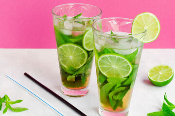 Non-alcoholic cold mojito in two glass glasses. Lemonade with lime and mint on a light background