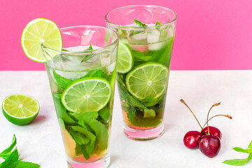 Non-alcoholic cold mojito in two glass glasses. Lemonade with lime and mint on a light background,