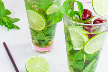 Non-alcoholic cold mojito in two glass glasses. Lemonade with lime and mint on a light background,